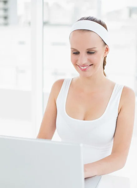 Joyful pretty sportswoman using a laptop — Stock Photo, Image