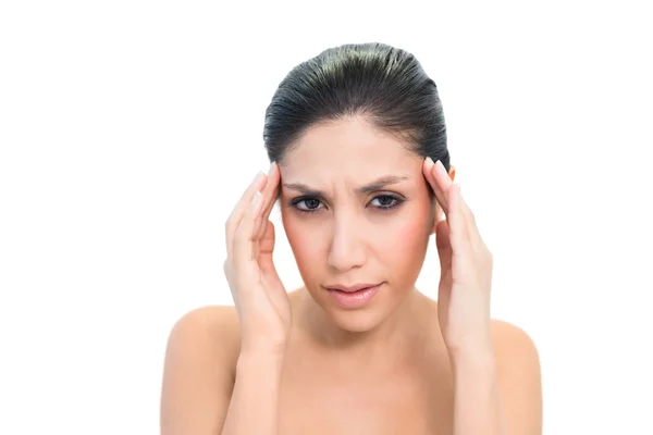 Frowning brunette with a headache touching her temples — Stock Photo, Image