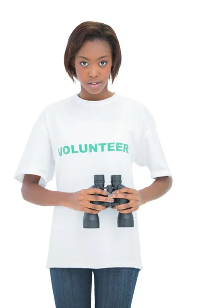 Serious woman holding binoculars looking at the camera — Stock Photo, Image