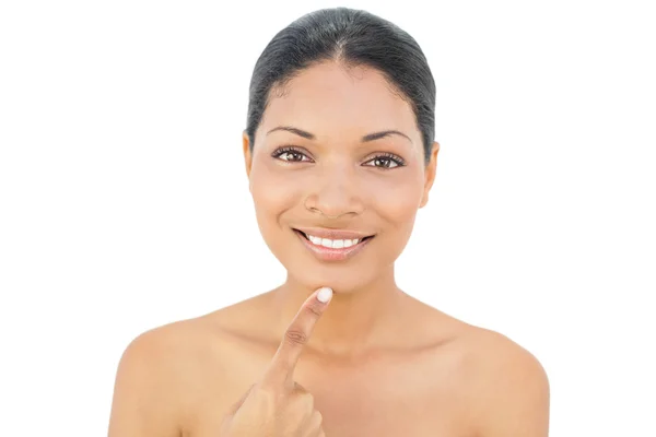 Smiling black haired model pointing at her chin — Stock Photo, Image
