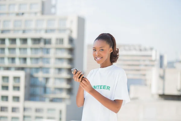 Fröhliche Freiwillige hält ihr Handy in der Hand — Stockfoto