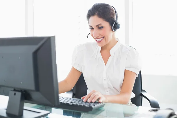 Cheerful call centre agent working at her desk on a call Royalty Free Stock Images
