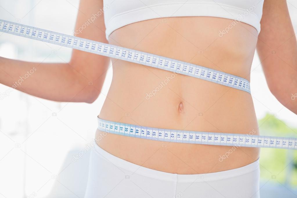 Slender woman measuring her waist during diet
