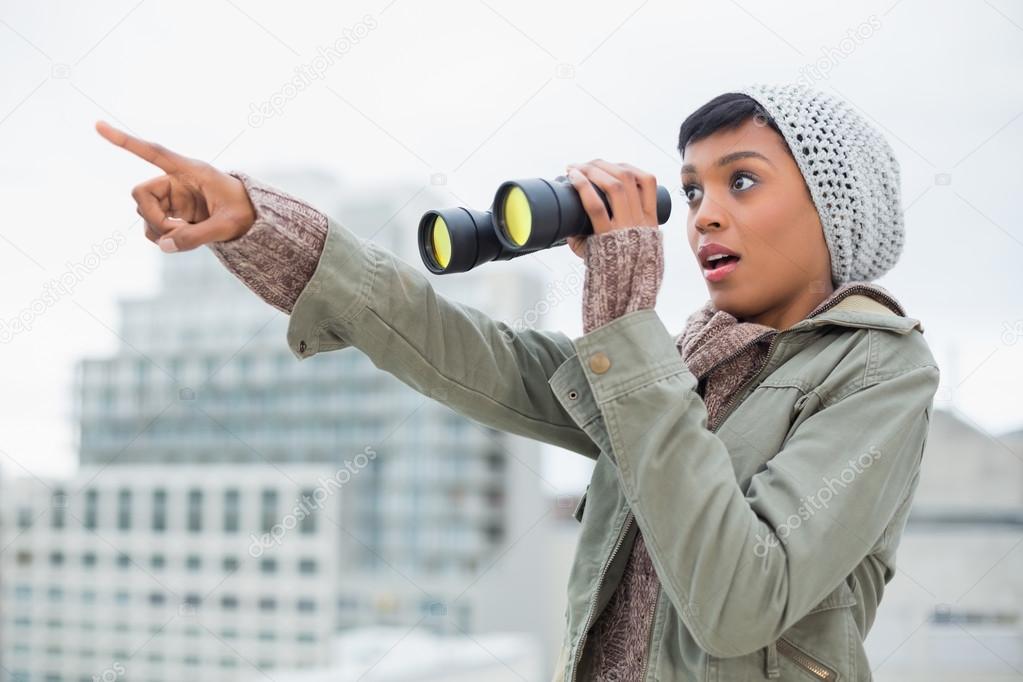 Shocked young model in winter clothes showing something in the sky