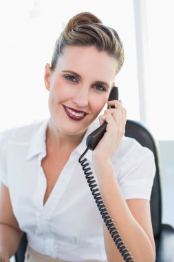 Gülümseyen iş kadını telefonda konuşuyor.