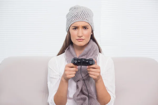 Frowning brunette with winter hat on playing video games — Stock Photo, Image