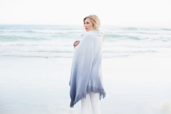 Pensive blonde woman warming herself in a blanket — Stock Photo, Image