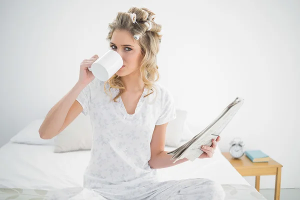 Peaceful cute blonde wearing hair curlers drinking coffee — Stock Photo, Image