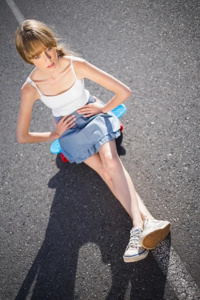 Jeune femme branchée assise sur son skateboard — Photo