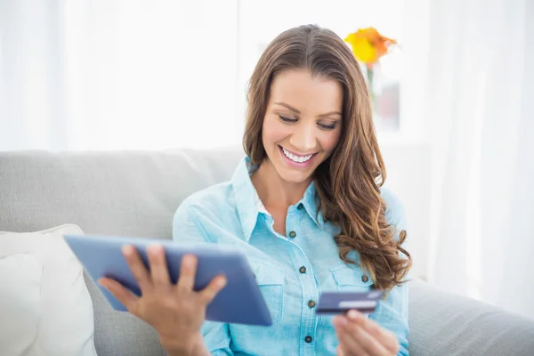 Attractive brunette holding tablet and credit card — Stock Photo, Image