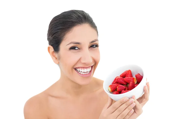 Aantrekkelijke brunette holding een kom verse aardbeien en glimlachen op camera — Stockfoto