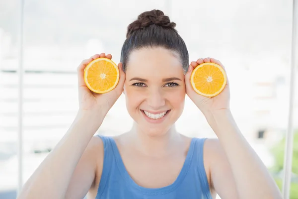 Mulher esbelta alegre em sportswear segurando fatias de laranja — Fotografia de Stock