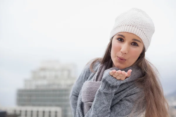 Pretty brunette with winter clothes on sending an air kiss to camera — Stock Photo, Image