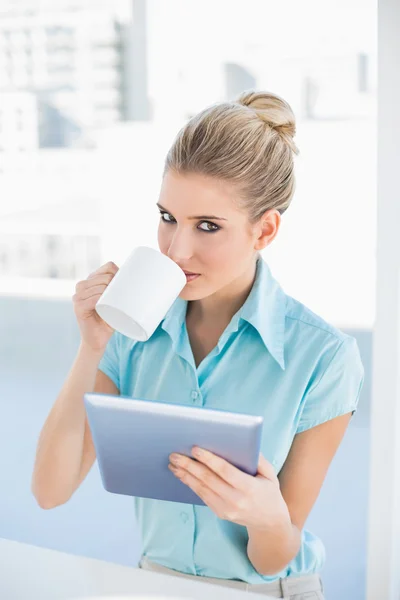 Donna elegante grave che utilizza tablet mentre beve caffè — Foto Stock