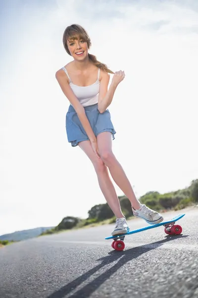 Cheerful young woman balancing on her skateboard — Stock Photo, Image