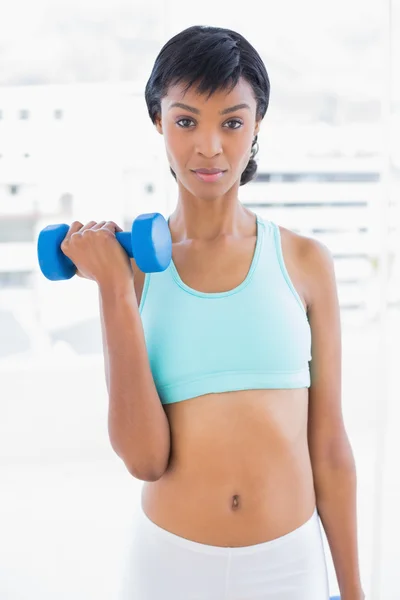 Stern black haired woman holding a dumbbell — ストック写真