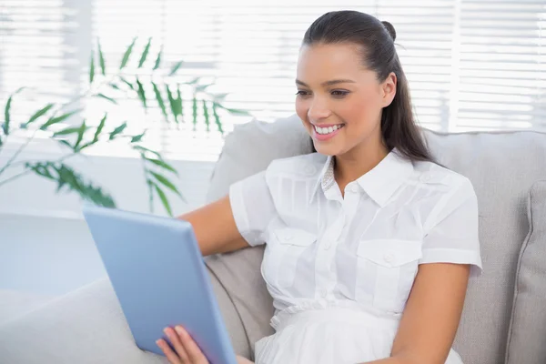 Gelukkig leuke vrouw met behulp van Tablet PC zittend op de gezellige sofa — Stockfoto