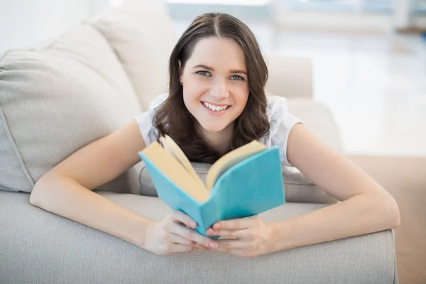 Vreedzame leuke vrouw liggend op een gezellige Bank lezen van boek — Stockfoto