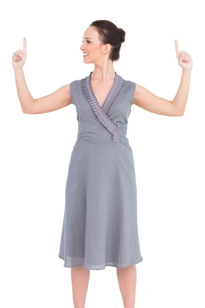 Cheerful elegant woman in classy dress pointing fingers up — Stock Photo, Image