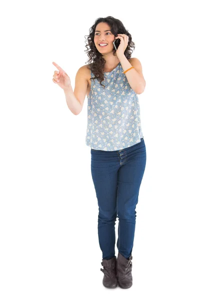 Attractive brunette pointing at something while having phone call — Stock Photo, Image