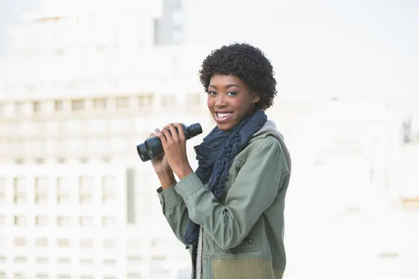 Smiling casual model holding binoculars — Stock Photo, Image