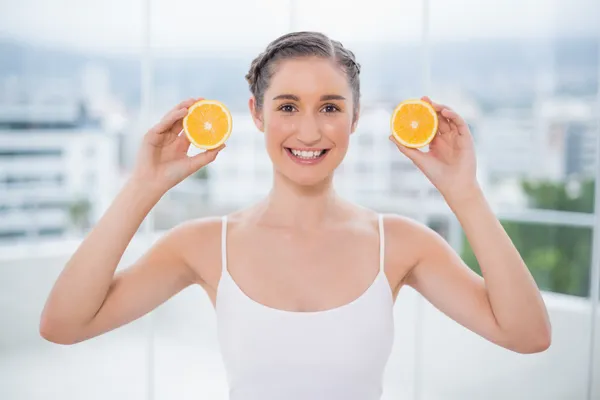 Feliz morena sana sosteniendo rodajas de naranja — Foto de Stock