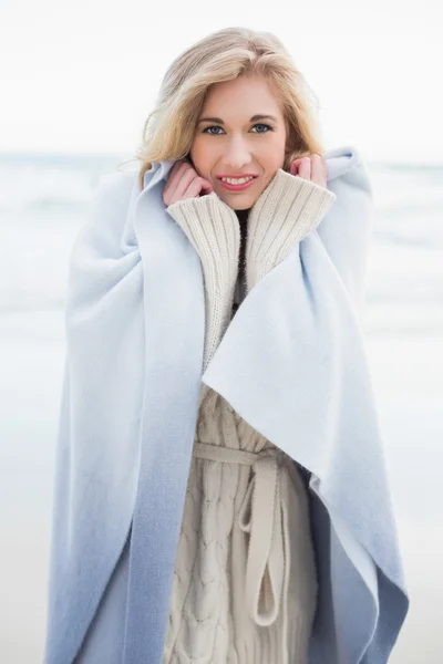 Lachende blonde vrouw over zichzelf in een deken — Stockfoto