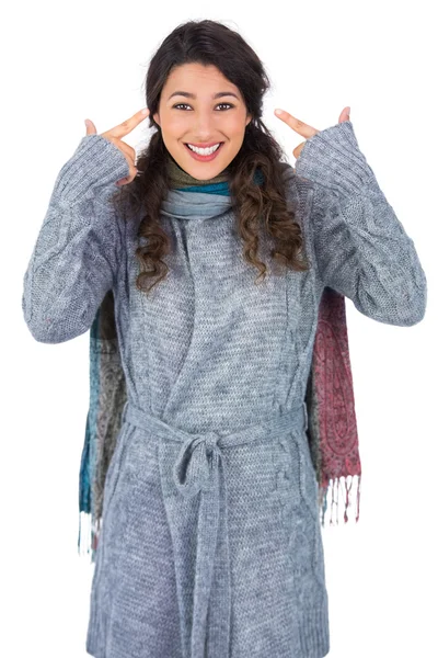 Kıvırcık saçlı model başını işaret kış giysileri ile gülümseyen — Stok fotoğraf
