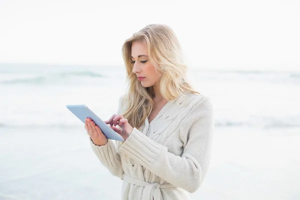 Pensive blonde woman in wool cardigan using a tablet pc — Stock Photo, Image