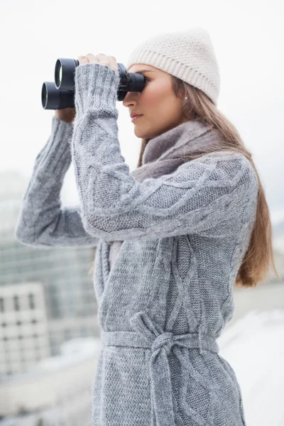 Mulher linda com roupas de inverno em olhar através de binóculos — Fotografia de Stock