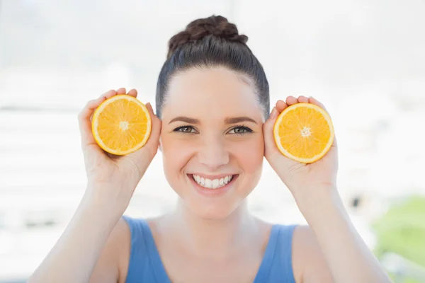 Mujer delgada sonriente en ropa deportiva sosteniendo rebanadas de naranja — Foto de Stock
