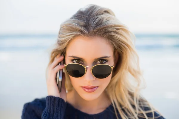 Ernste wunderschöne Blondine am Telefon, die über ihre Sonnenbrille schaut — Stockfoto