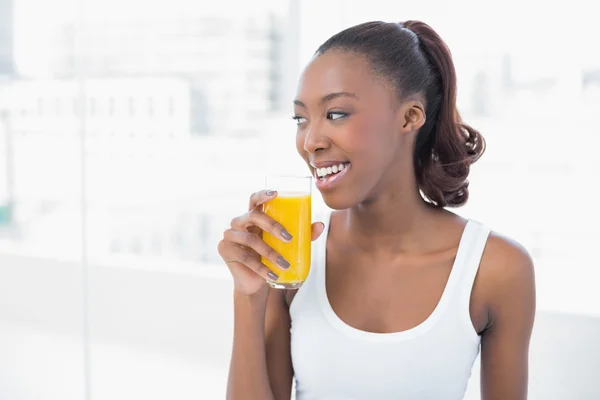 Cheerful sporty model holding glass of orange juice — Stock Photo, Image
