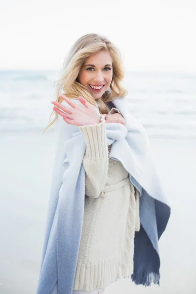 Happy blonde woman in a blanket waving at the camera — Stock Photo, Image