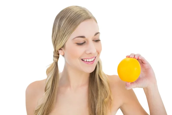 Mujer rubia joven agradable mirando una naranja — Foto de Stock