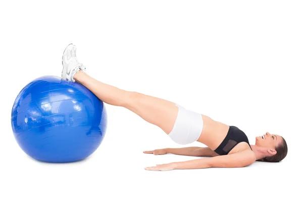 Visão lateral da mulher sorrindo apto deitado trabalhando com bola de exercício — Fotografia de Stock