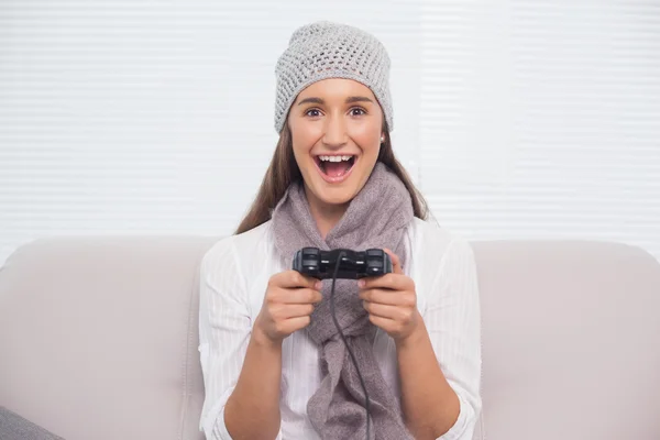 Lachende brunette met winter hoed op het spelen van videospellen — Stockfoto