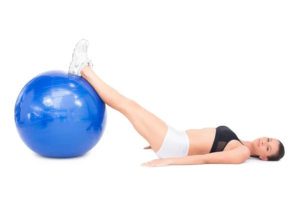 Vista laterale della donna in forma rilassata sdraiata che lavora con la palla da ginnastica — Foto Stock