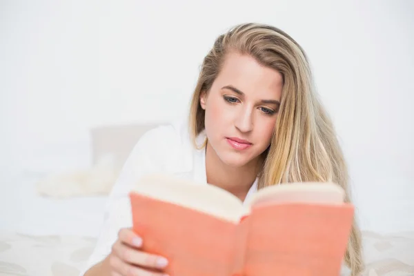 Relajado hermosa modelo acostado en la cama acogedora libro de lectura —  Fotos de Stock