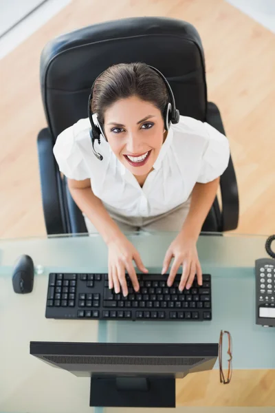 Gelukkig call center agent te typen terwijl hij op een oproep — Stockfoto