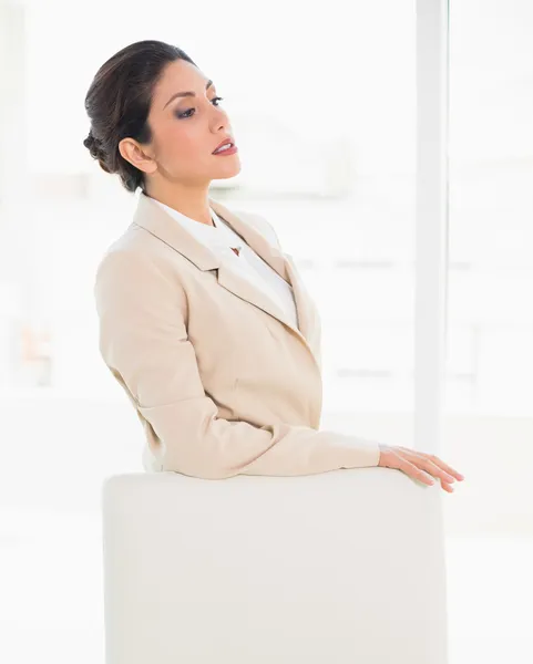 Хмурая деловая женщина, стоящая за стулом — стоковое фото
