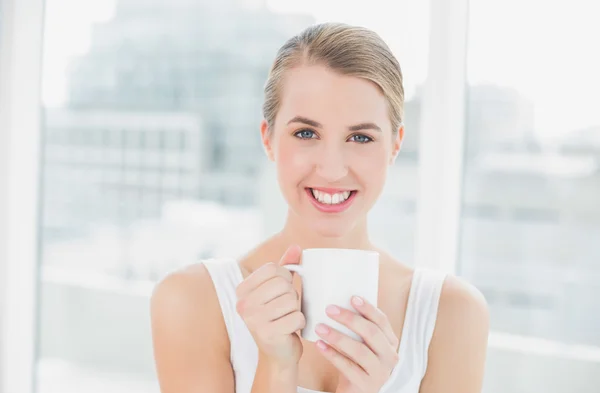 Mujer rubia sonriente sosteniendo una taza de café — Foto de Stock