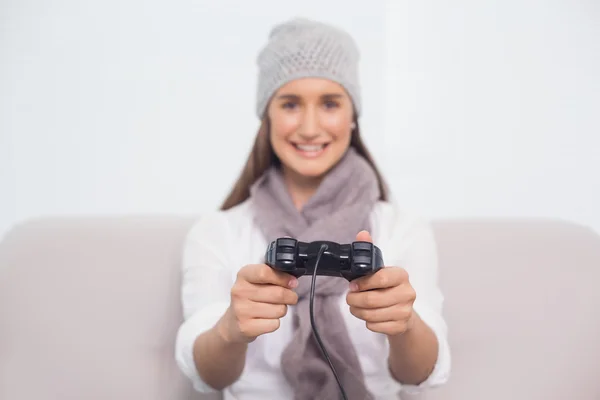 Cheerful brunette with winter hat on playing video games — Stock Photo, Image