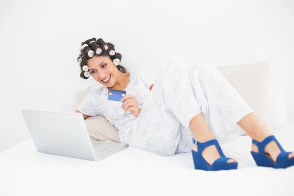 Morena em rolos de cabelo e sapatos cunha usando seu laptop para compras on-line — Fotografia de Stock