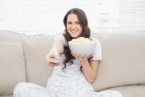 Mujer bonita en pijama tomando palomitas mientras ve la televisión — Foto de Stock