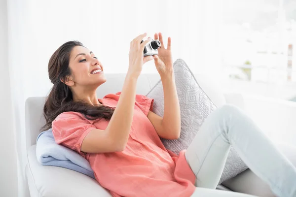 Brünette sitzt auf ihrem Sofa und fotografiert — Stockfoto