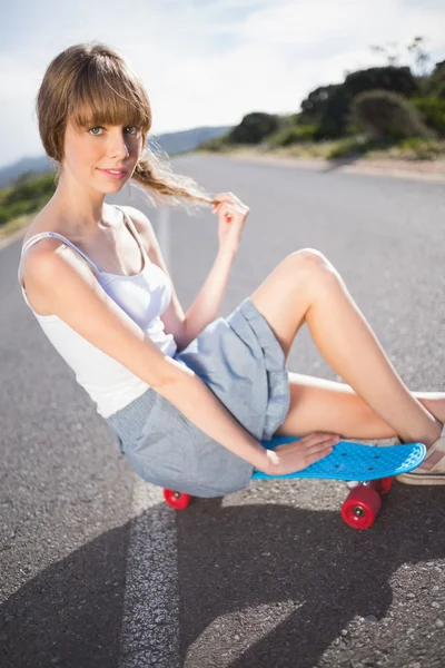 Flippige junge Blondine sitzt auf ihrem Skateboard — Stockfoto