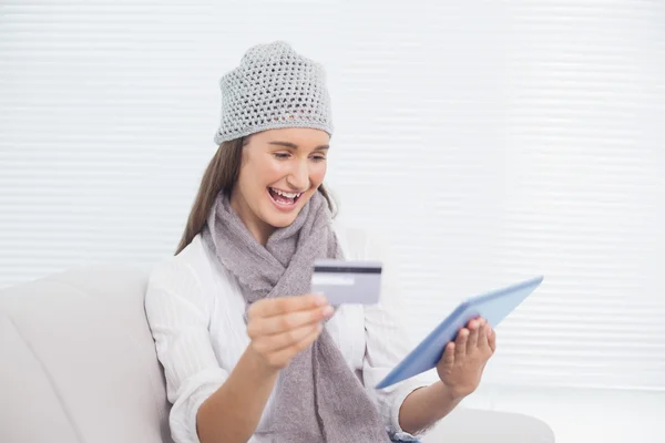 Smiling pretty brunette with winter hat on buying online — Stock Photo, Image