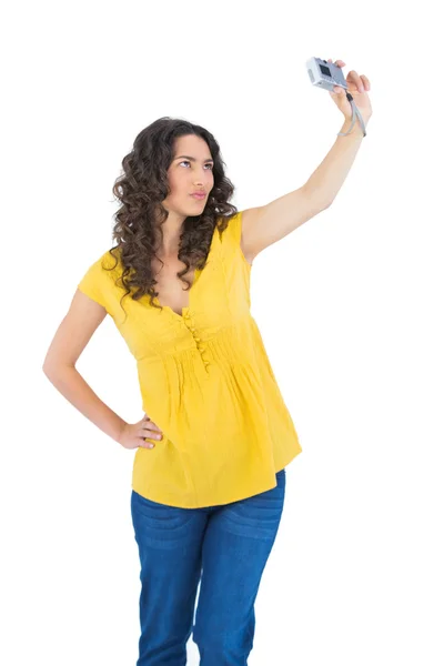 Serious curly haired brunette taking picture of herself — Stock Photo, Image