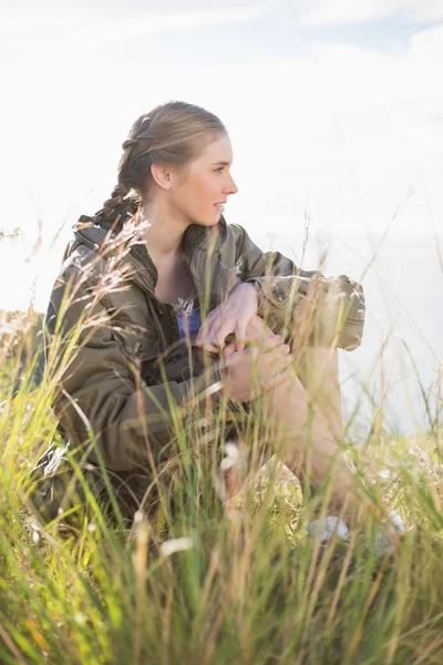 Blonde woman sitting in grass — Stock Photo, Image